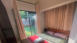 Un dormitorio con cama, televisor y puerta corrediza de vidrio a un balcón.
