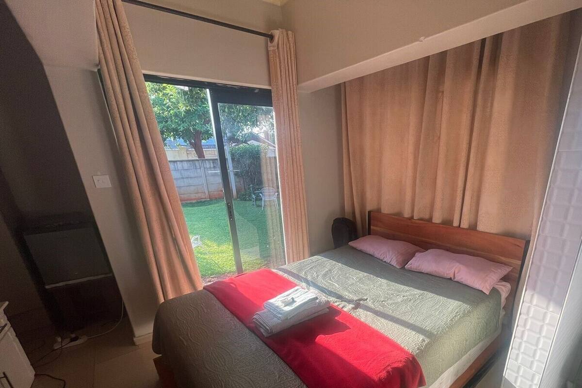 A bedroom with a bed, a TV, and a sliding glass door to a balcony.