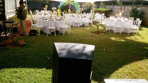 Evento al aire libre con carpas blancas, mesas redondas y sillas.