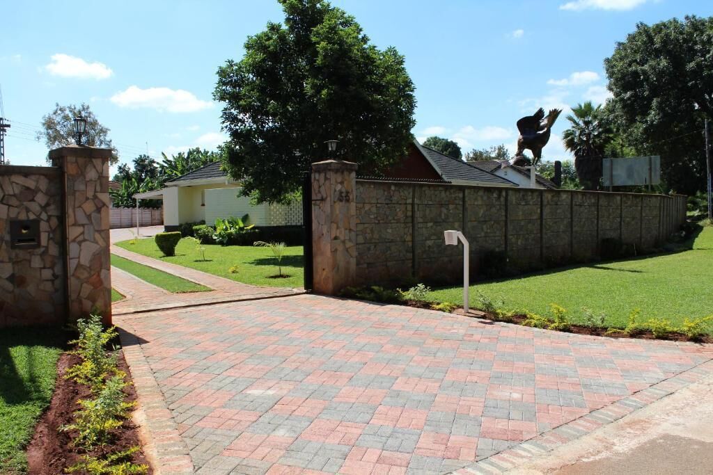 A paved driveway leading to a stone wall with a statue on top.