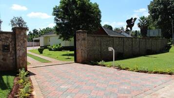 A paved driveway leading to a stone wall with a statue on top.