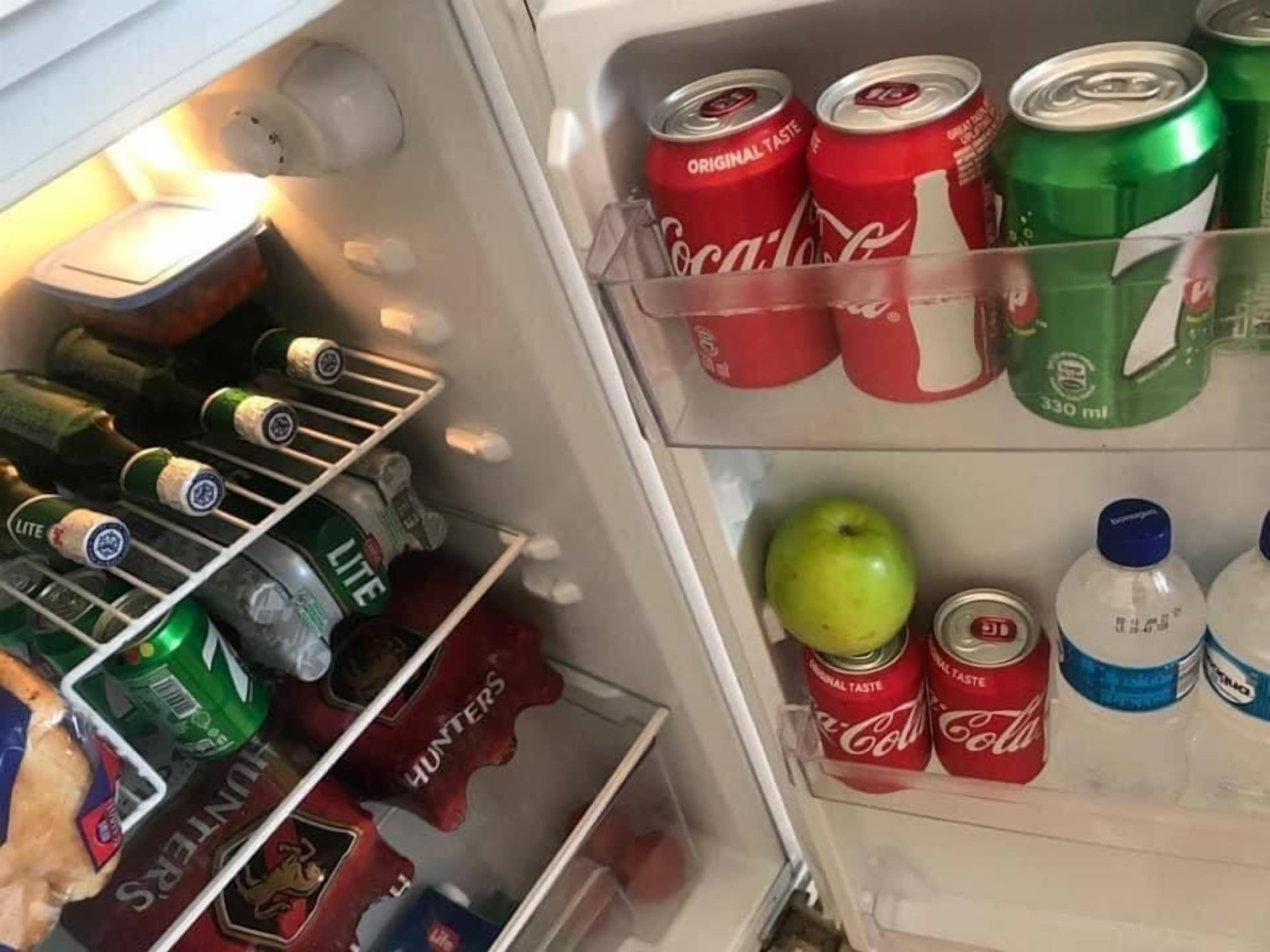 A refrigerator stocked with various beverages including Coca-Cola, 7UP, and beer.