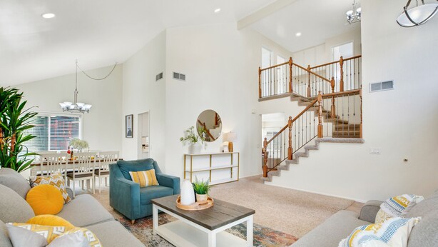 Ein geräumiges Wohnzimmer mit hoher Decke, einer Treppe und einem Essbereich.