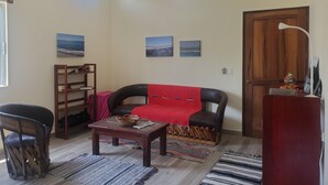 A living room with a sofa, a coffee table, a wooden chair, a bookshelf, and a door.