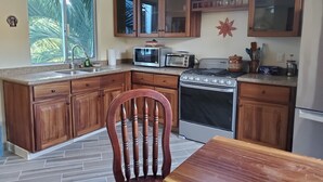 A kitchen with wooden cabinets, a stove, a microwave, and a sink.