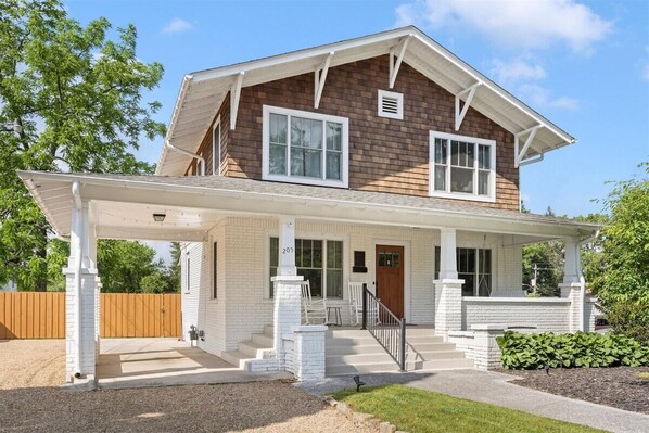 A two-story house with a covered porch, a front door, and a number '205' sign.