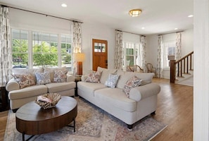 A living room with a sofa set, a coffee table, and a staircase.