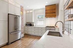 Enjoy cooking in this kitchen with a stainless steel refrigerator, stove, and sink, plus a window with a view of the outdoors.