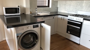 Une cuisine compacte équipée d’un lave-linge, d’un four à micro-ondes, d’un lave-vaisselle et d’une cuisinière.