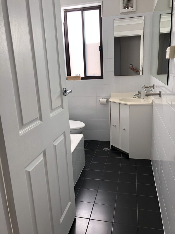Un baño pequeño y moderno con inodoro, lavamanos y espejo.