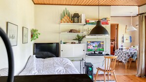 A bedroom with a bed, a TV, a computer setup, and a desk with a chair.