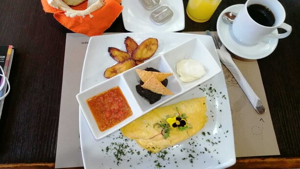 Un plato de desayuno con tostadas, papas fritas, un huevo escalfado y una porción de salsa.
