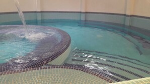 A hot tub with a tiled edge and a water feature. - Asgard Resort (Santiago Sacatepéquez)