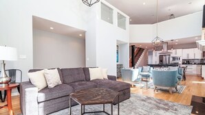A spacious living area with a grey sectional sofa, a coffee table, and a dining set. - Eclectic, Stylish, and Cozy Milwaukee Home! (Milwaukee)