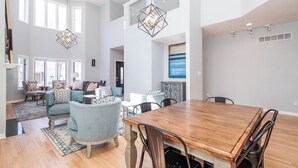 A spacious living area with a wooden dining table, light blue armchairs, and a modern chandelier. - Eclectic, Stylish, and Cozy Milwaukee Home! (Milwaukee)