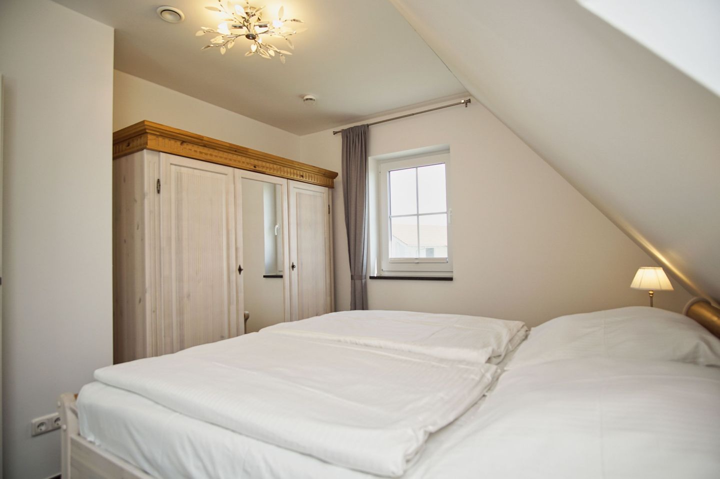 A bedroom with a bed, a window, a wardrobe, and a ceiling light.