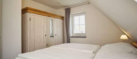 A bedroom with a bed, a window, a wardrobe, and a ceiling light.