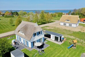 A house with a large patio, a garage, and a play area with a slide. - Villa Morgensünn - House in an idyllic location with sauna, terrace and garden - (Trent)