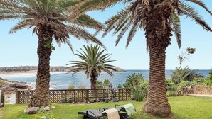 Une terrasse avec deux chaises longues et une petite table, d’où l’on a vue sur une plage et l’océan.