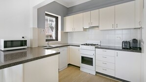 Une cuisine moderne avec des meubles blancs, un four à micro-ondes, une cuisinière et un lave-vaisselle.