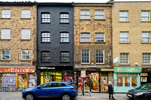 A street view with a blue car parked in front of a store named 'TOWER | BRICK LANE'.