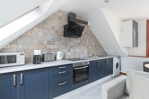 A compact kitchen with a microwave, toaster, kettle, and oven.