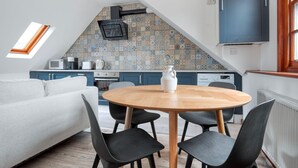 Eine moderne Küche mit schrägen Wänden, einem Essbereich mit rundem Tisch und Stühlen sowie einem eingebauten Backofen.