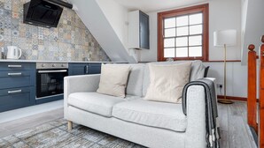 Eine moderne Küche mit Backofen, einem grauen Sofa und einer Wandverkleidung mit Muster.