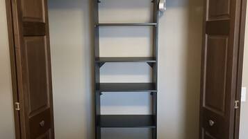 Ein begehbarer Kleiderschrank mit Einbauschränken und einem großen Spiegel.