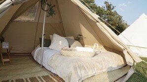 Una carpa acogedora con una cama, almohadas, una cesta y un cartel de bienvenida.