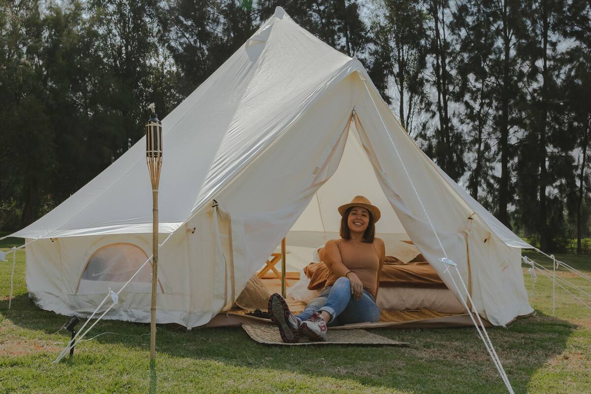A person sitting inside a tent with a view of trees in the background.