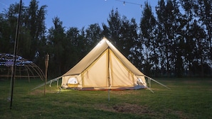 Una carpa montada en un campo cubierto de hierba, con luces colgantes.