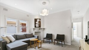Una sala de estar moderna con un sofá seccional gris, dos sillones, una mesita de madera y una chimenea.