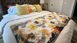 Ein Schlafzimmer mit einer gesteppten Kopfteil, einer zudeckenden Bettdecke mit Blumenmuster und einer weißen Tür.