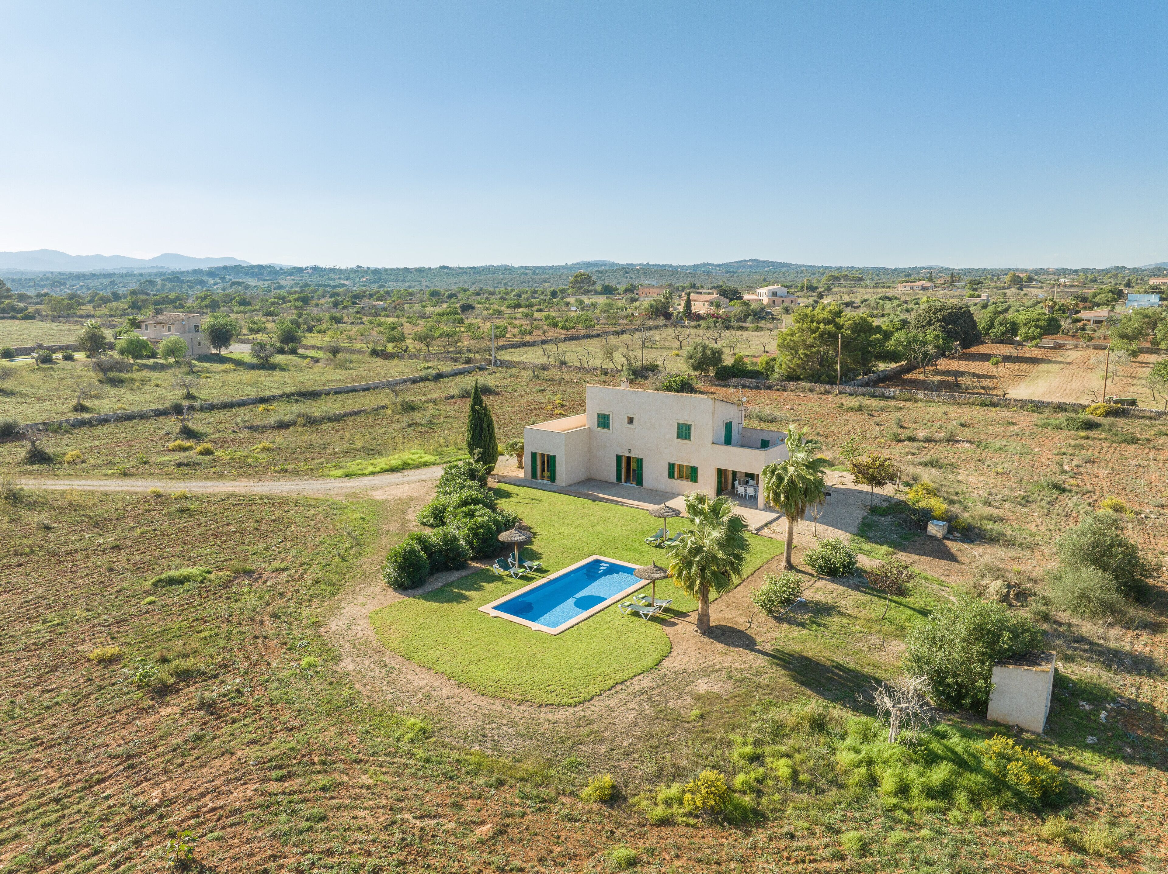 Una casa moderna con piscina, rodeada de césped y árboles.