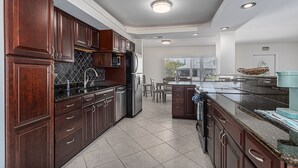 A modern kitchen with dark wooden cabinets, stainless steel appliances, and a large island with a granite countertop.