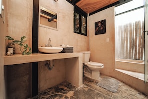 Uma casa de banho com lavatório, sanita e janela com cortinas.