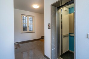 Un couloir avec une fenêtre, un ascenseur et une porte.