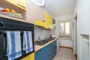 Eine kleine Küche mit Herd, Spüle und einem Fenster mit Aussicht.