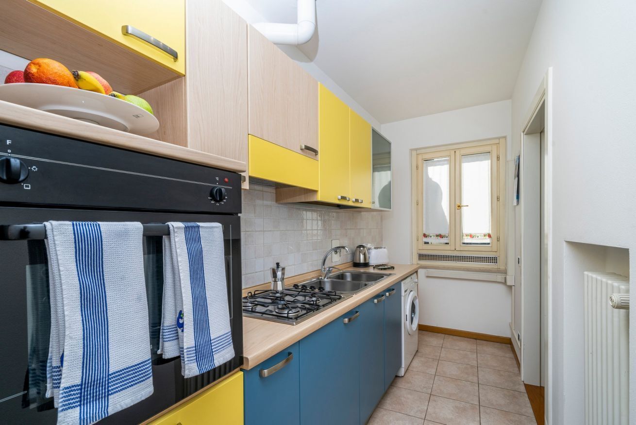 A compact kitchen with a stove, sink, and a window with a view.