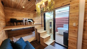 A wooden interior with a seating area, a staircase, and a view of an outdoor jacuzzi. - ZUMI TERRACE UCHINAAMIYA RESORT (Miyakojima)