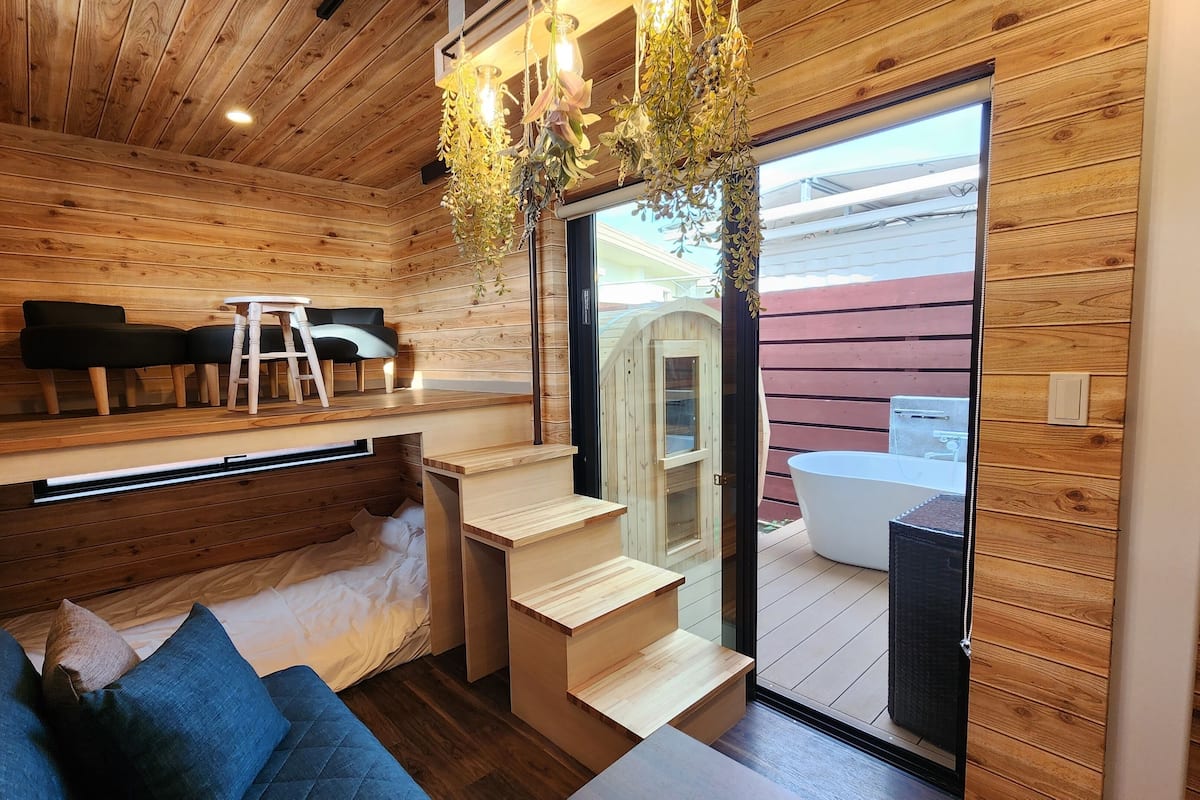 A wooden interior with a seating area, a staircase, and a view of an outdoor jacuzzi.
