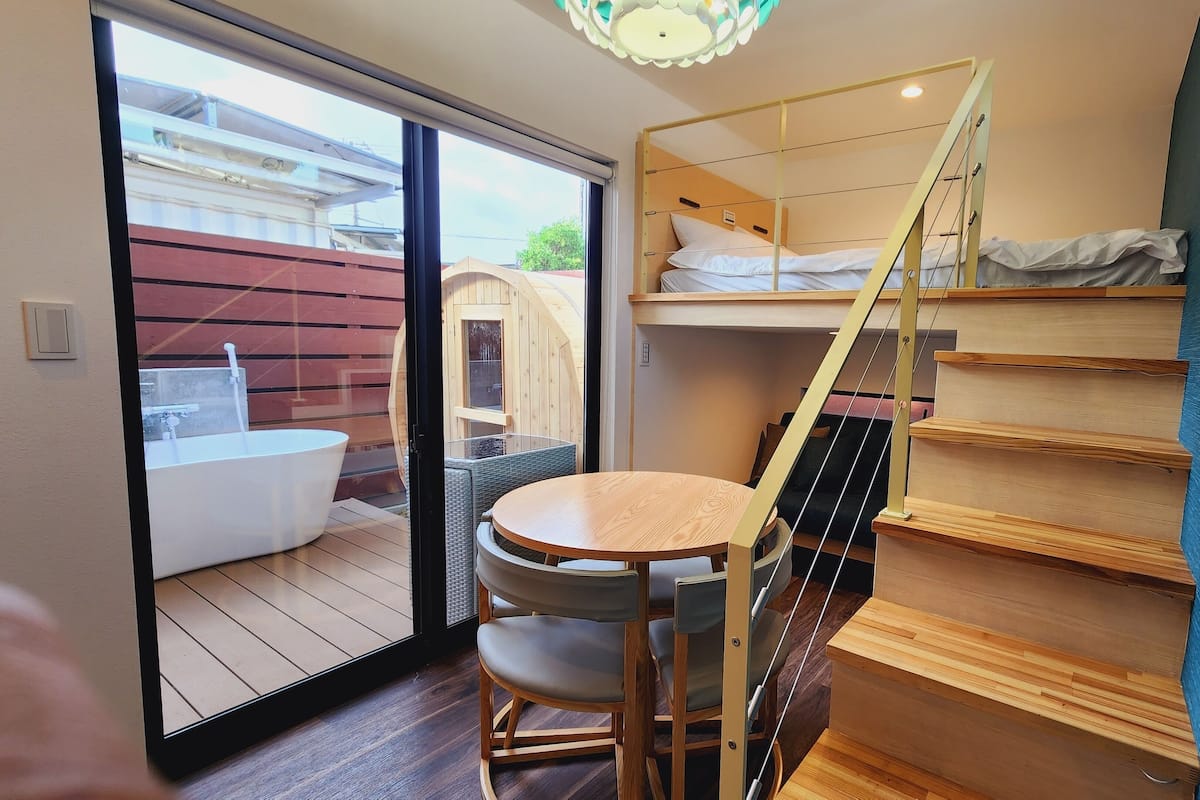 A compact room with a bunk bed, a small round table, and a chair.