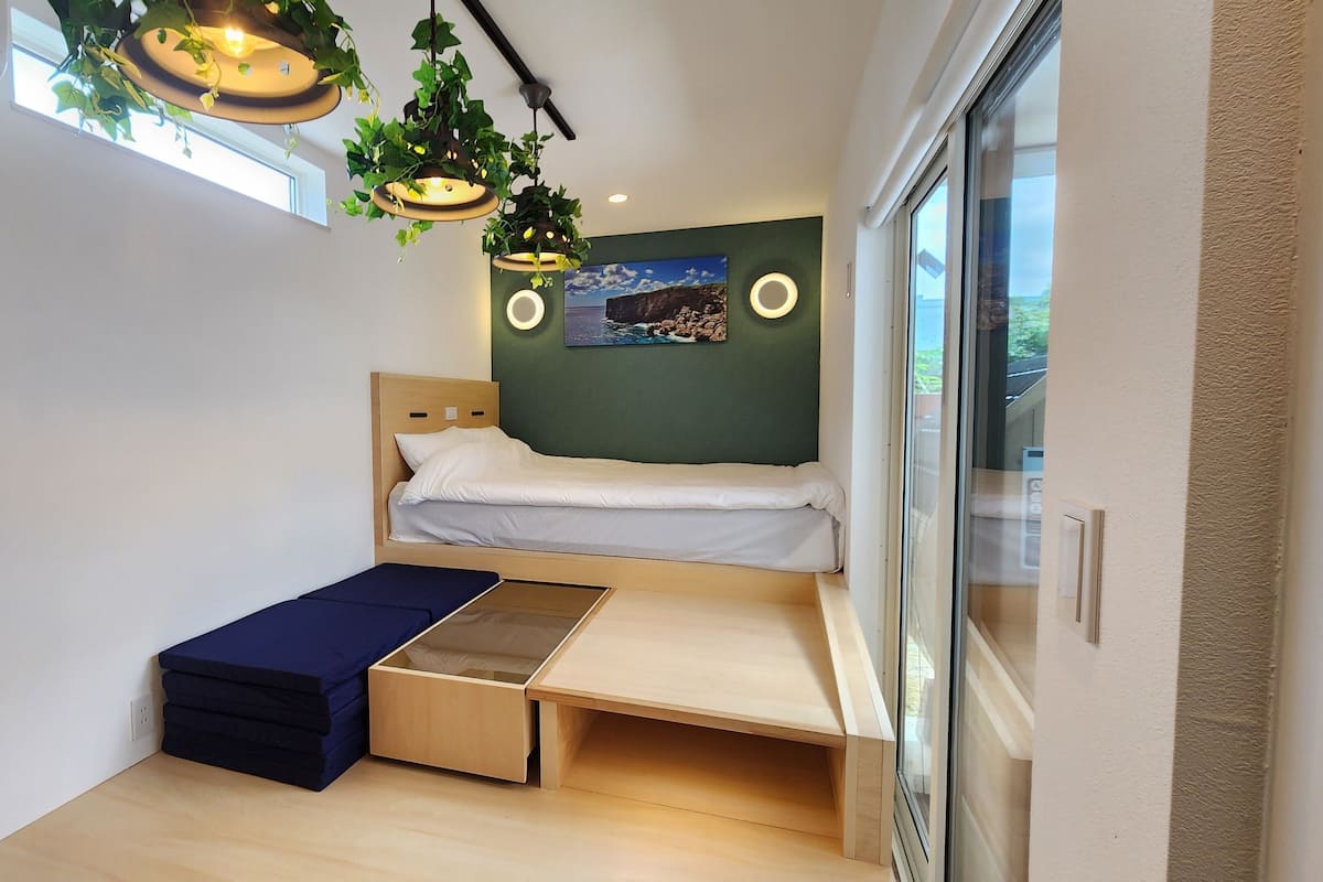 A compact room with a bed, a small desk, and a window.