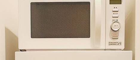 Un horno microondas Hisense con pantalla digital y botones de control sobre un refrigerador blanco.