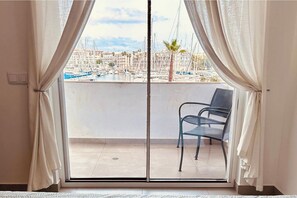 Un balcon donnant sur une marina, une chaise et un rideau.