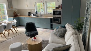 Een moderne keuken met een eethoek, voorzien van een bank, salontafel en een groot raam.