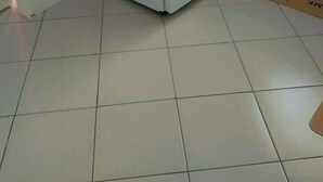 Een keuken met een witte koelkast, een betegelde vloer en een raam met gordijnen.