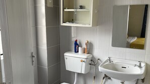 Een badkamer met toilet, wastafel, spiegel en kast.