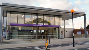 A modern train station with a clear sign for the 'Acton Main Line'.
